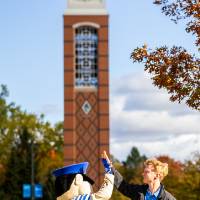 guy giving Louie the Laker mascot a high five in front of clocktower